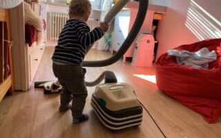 Ein Kind Hilft im Haushalt indem es sein Kinderzimmer gerne selbst saugt.