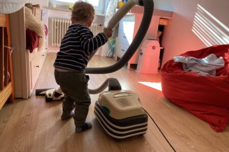 Ein Kind Hilft im Haushalt indem es sein Kinderzimmer gerne selbst saugt.