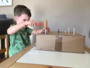 Ein Kind hämmert mit Hammer und Golf Tees