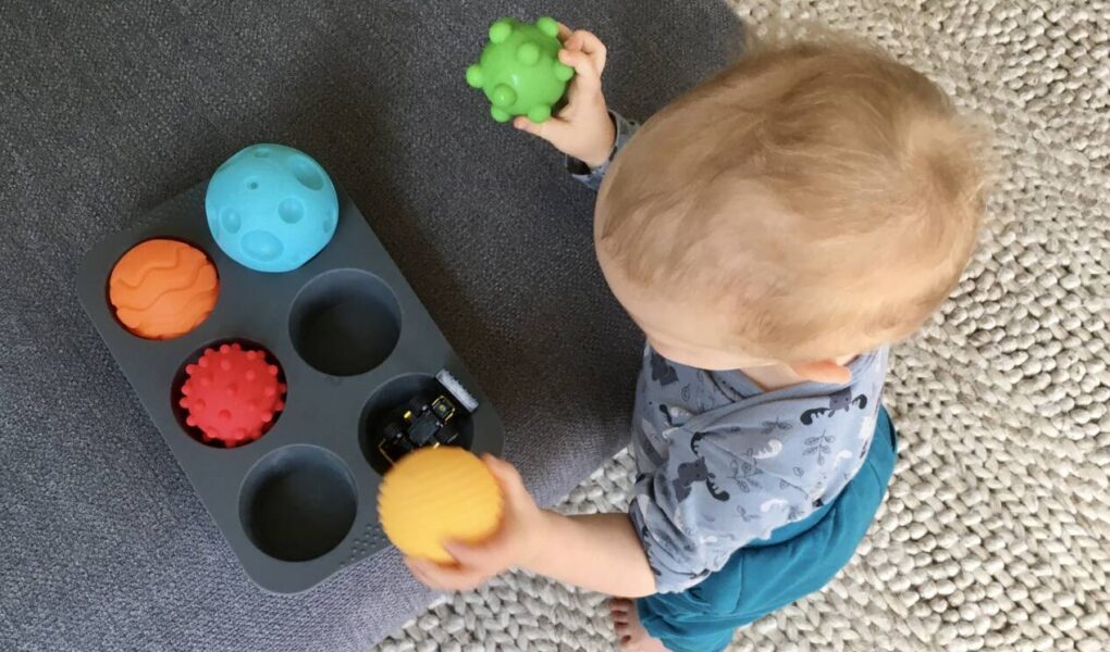 Ein Baby räumt Bälle in Muffinformen